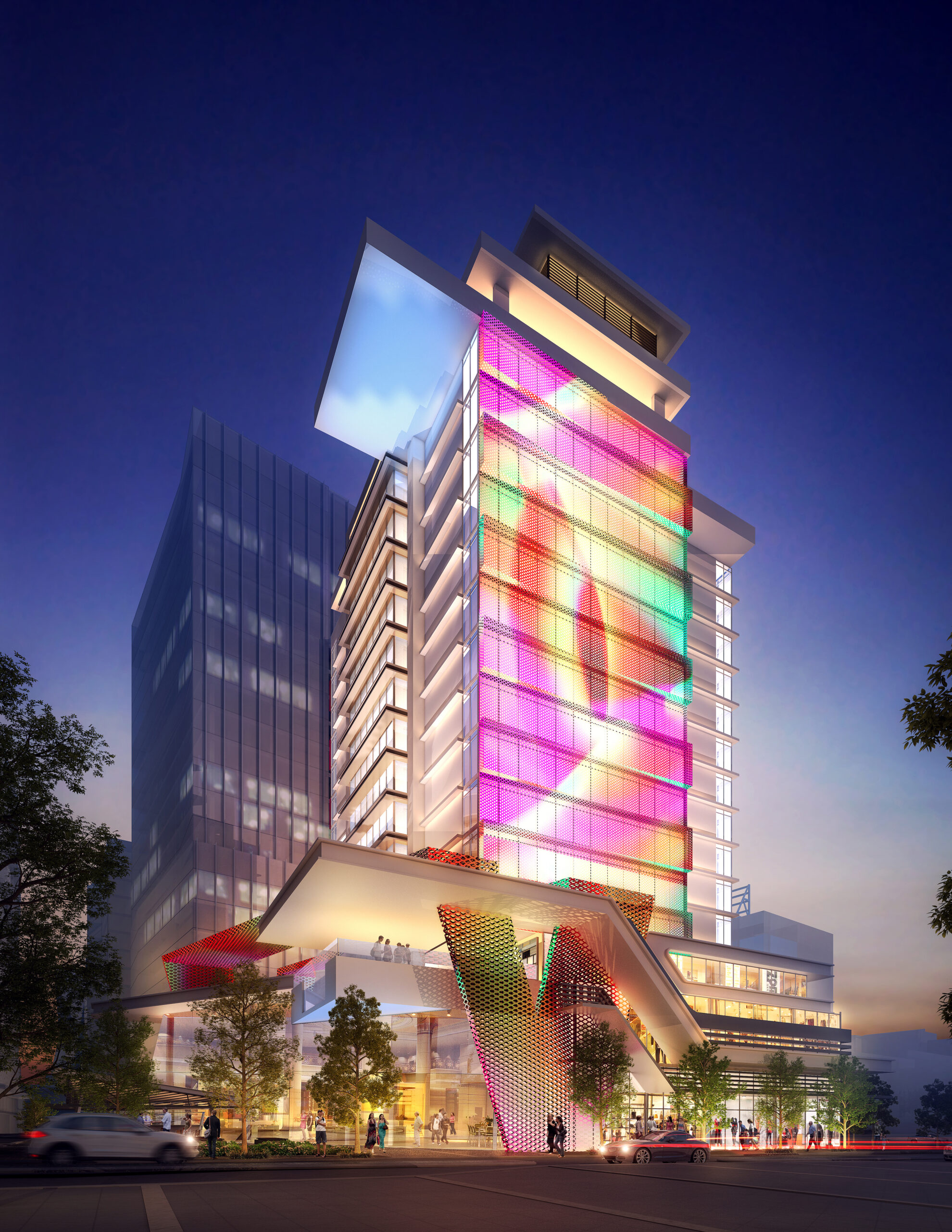 Hotel building with an illuminated facade extending the entire length, projecting vibrant colors across its face. The retail tenancies on the ground level of the podium are also illuminated, bustling with people. The image captures a lively scene at dusk